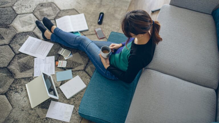 Woman Sits Living Room Drinking Coffee Reviewing Personal Finances Istock 1373622269.jpg