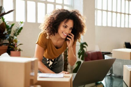 Businesswoman On Phone While Using Laptop In Office Morsa Images 3.jpg